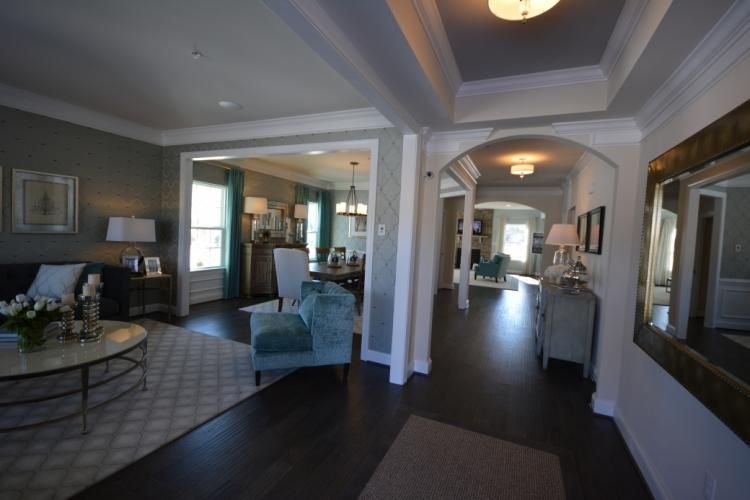 Spacious home interior with dark wood floors, light walls, and multiple rooms visible through doorways.