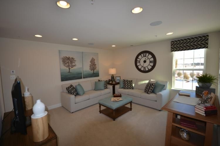 Living room with two white sofas, artwork, and a round clock on the wall.