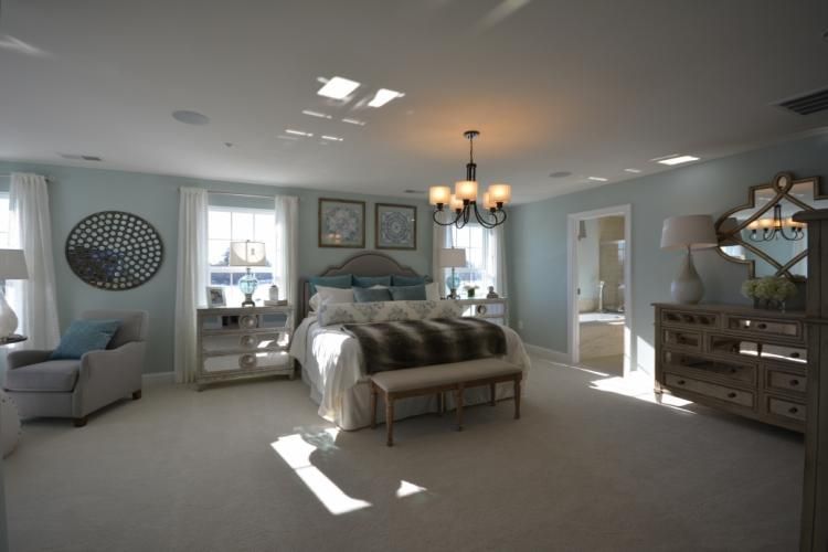 Spacious bedroom with light blue walls, large bed, and a mirrored dresser.