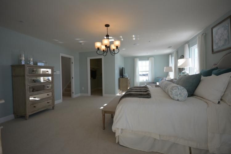 Spacious bedroom with blue walls, large bed, dresser, and chandelier.