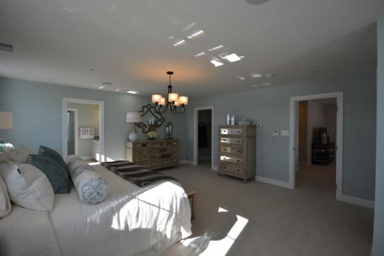 Spacious bedroom with blue walls, light carpet, several doorways, and a chandelier.