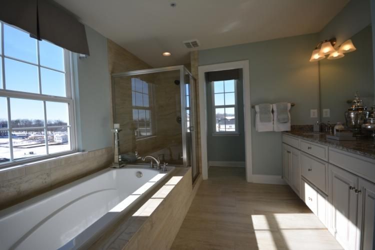 Bathroom with a tub, shower, vanity, and window with outdoor view.
