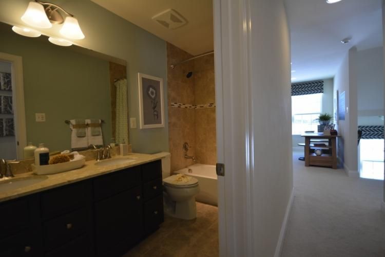 Bathroom with a double vanity and a view of a hallway with natural light.