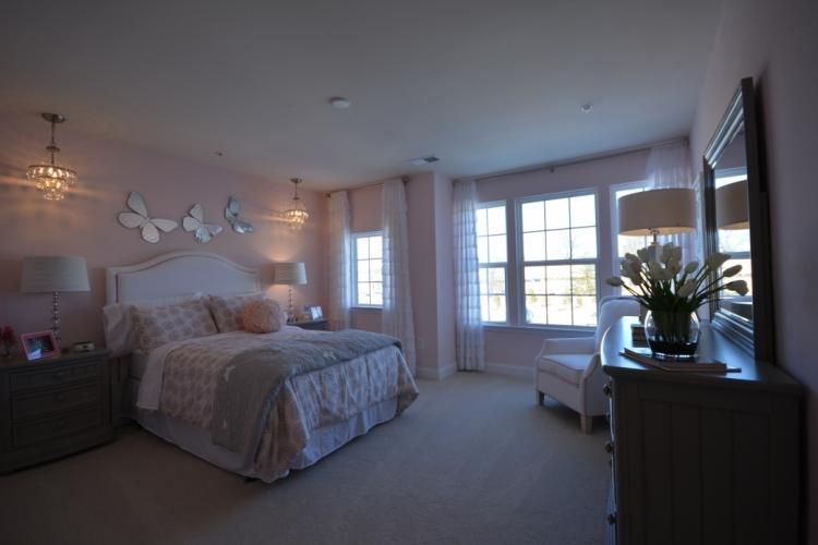 Pink bedroom with a bed, dresser, windows, and decorative butterflies on the wall.