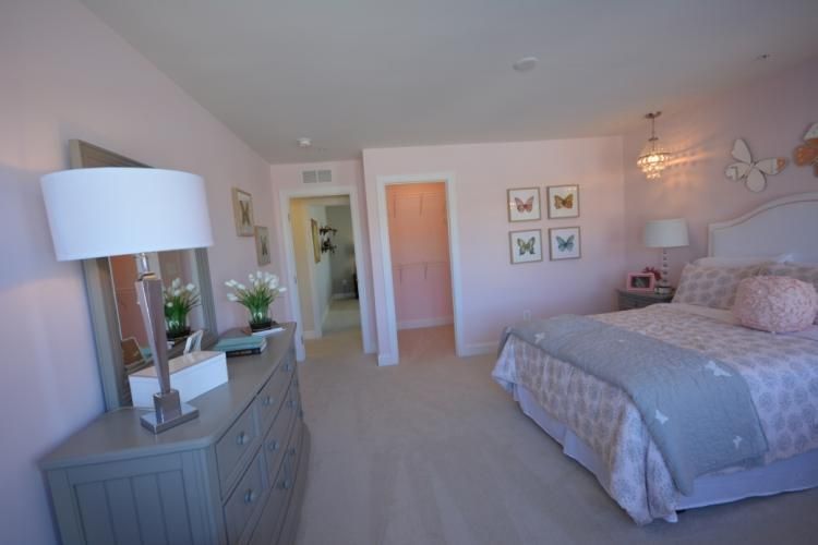 Pink bedroom with a gray dresser, bed, and butterfly decor.