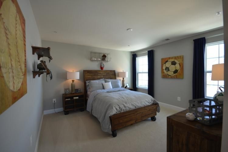 Bedroom with a wooden bed, nightstands, and artwork on light gray walls.