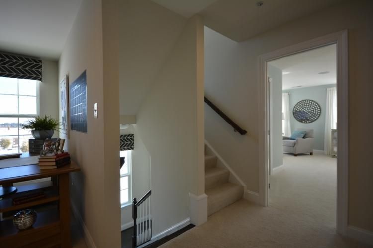 Hallway with stairs and doorway leading to a bedroom with light blue walls and decor.