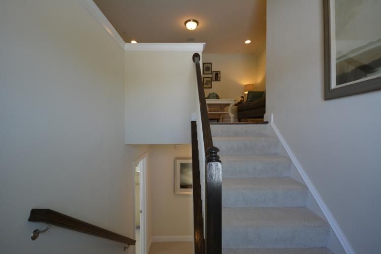 Staircase with carpeted steps leading upward; a landing overlooks the lower level.
