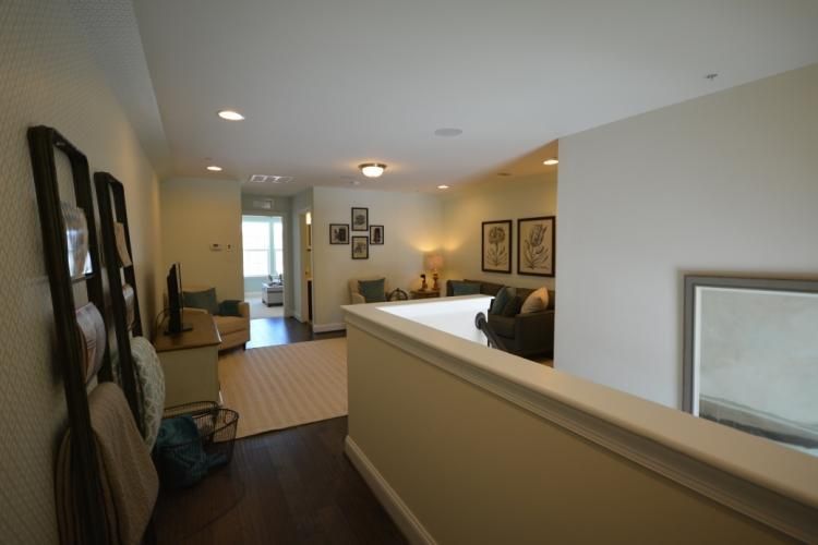Hallway with dark wood floor, leading to a living room with tan walls and furniture.