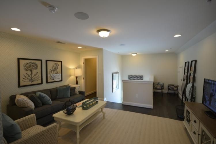 Living room with gray sofa, white coffee table, and TV on a console; neutral walls and carpet.