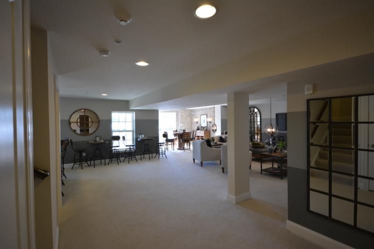 Spacious, open-concept living area with neutral color scheme. Dining table, seating area, and large mirror are visible.
