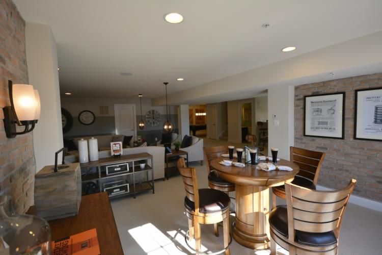 Interior of a lounge area with a brick wall, round wooden table, chairs, and recessed lighting.