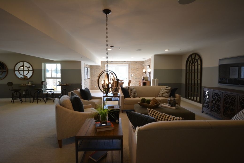 Spacious living room with light-colored couches, dark wood furniture, and a round clock.