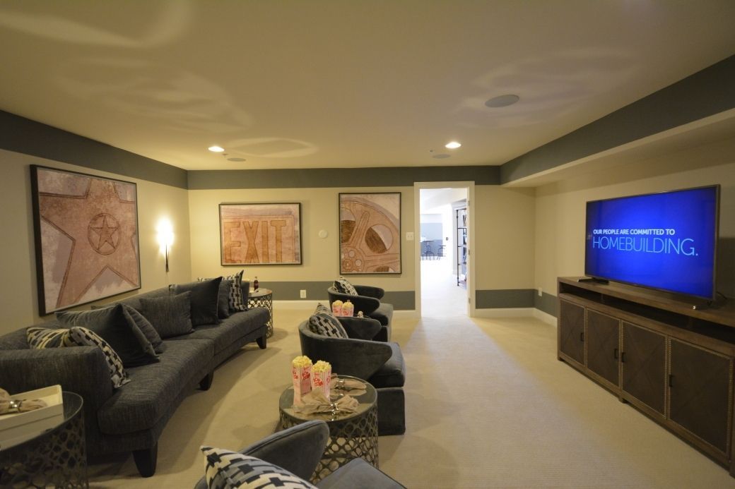 Living room with a curved blue sofa, two armchairs, artwork, and a TV on a cabinet.