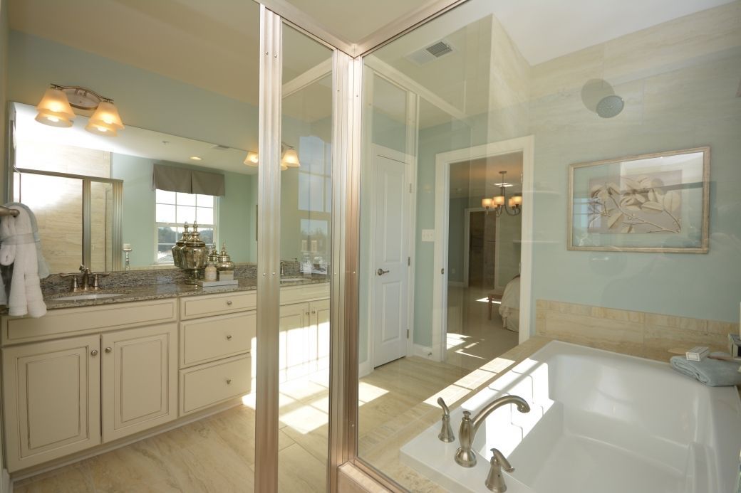 Spacious bathroom with glass shower, soaking tub, light blue walls, and vanity with double sinks.
