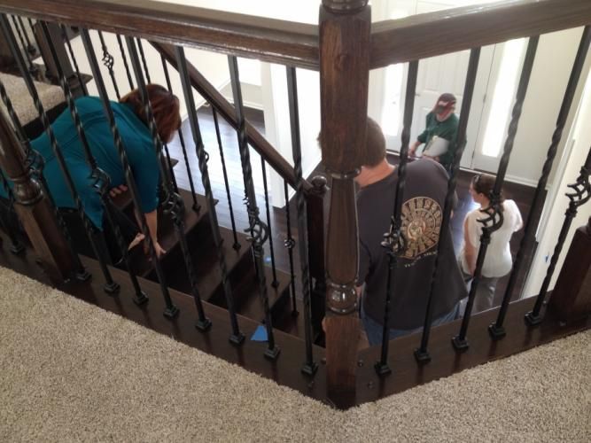 People on a dark wood staircase, some walking down, entering a home.