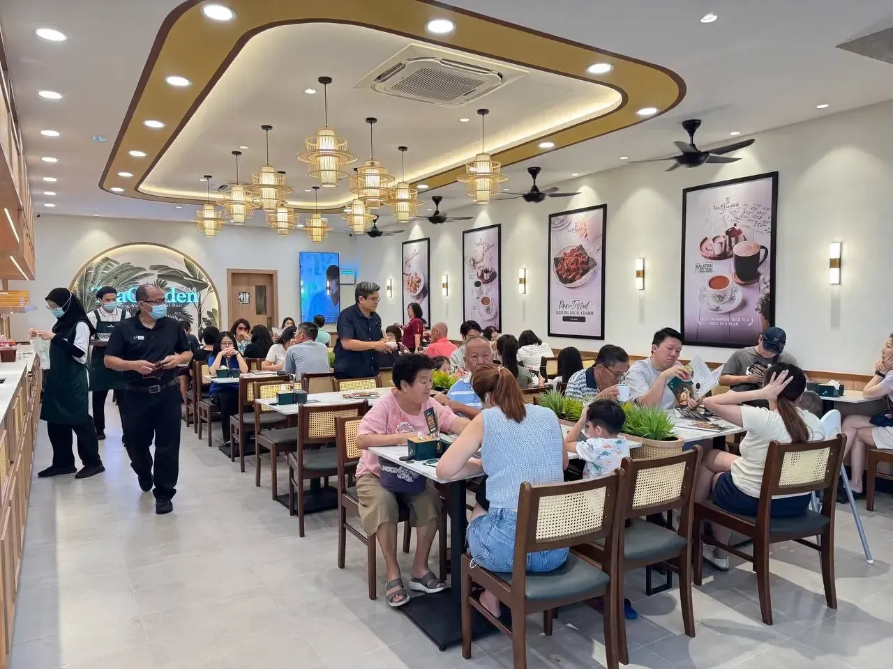 Bright restaurant interior with diners seated at tables and staff walking down the aisle