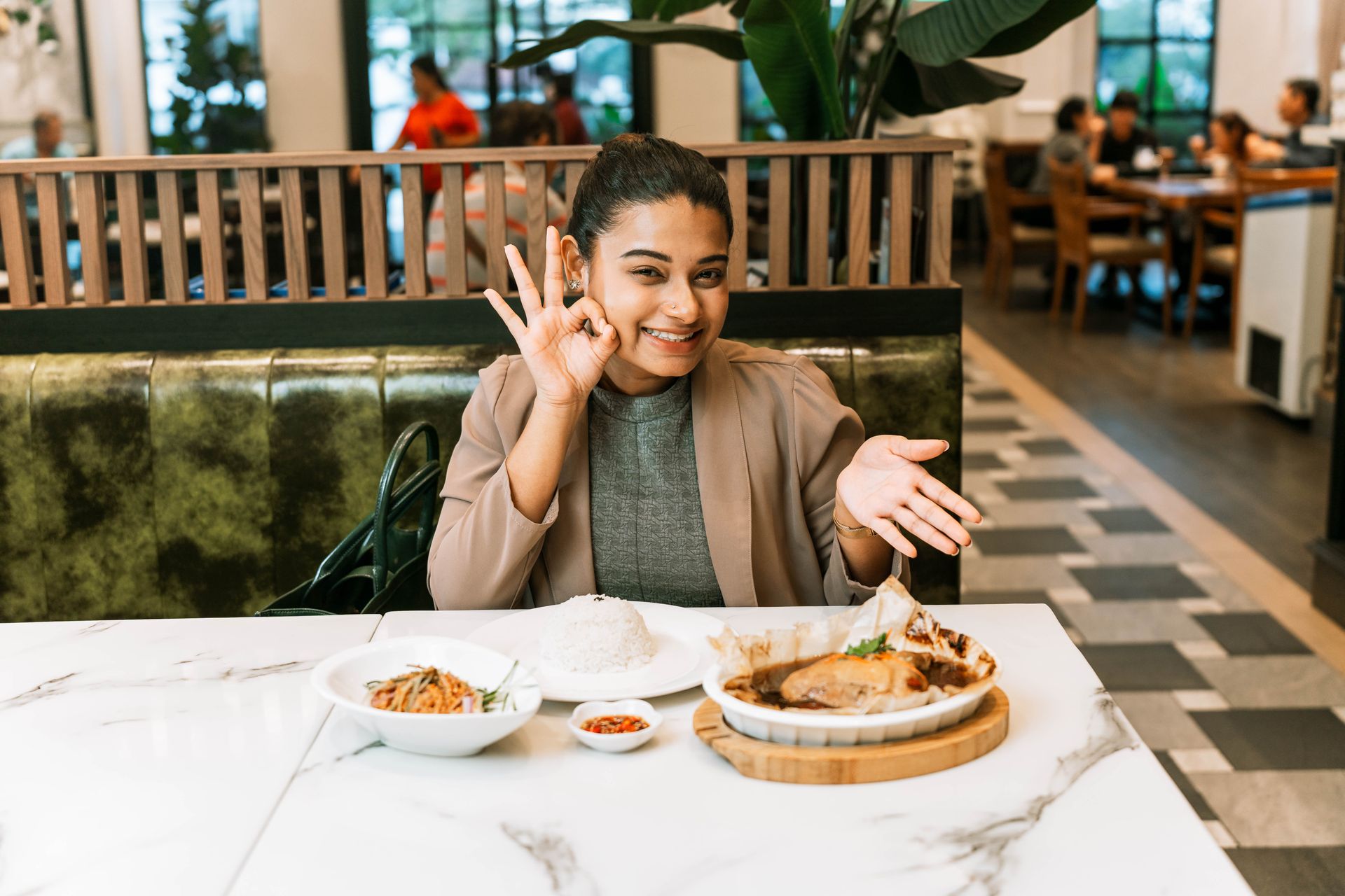 A fully satisfied female customer showing signs of approval for the food