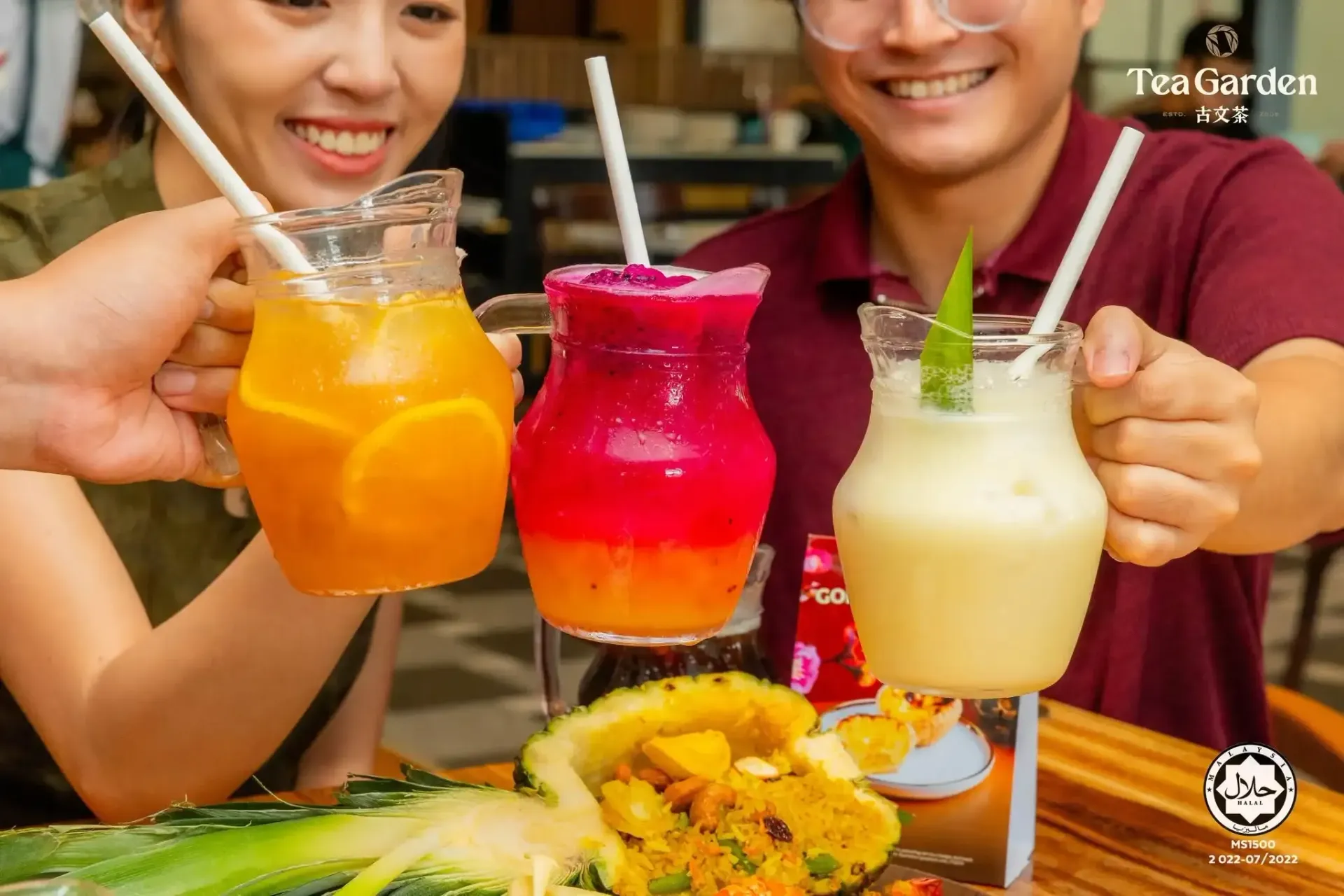 Three colorful tropical drinks held above a plate of food at an outdoor table.