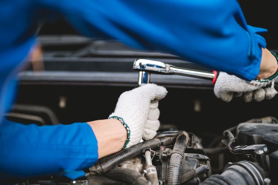 Mechanic using a ratchet wrench on an engine in a car repair shop