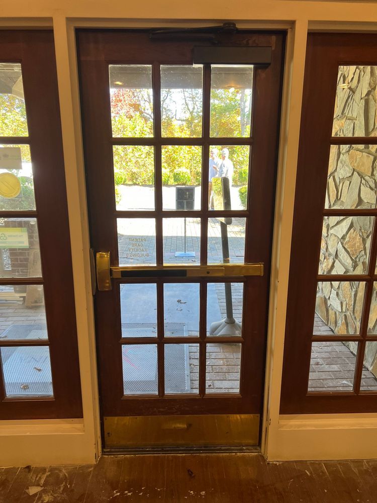 Wooden glass door with side windows opening to a sunlit deck and trees outside
