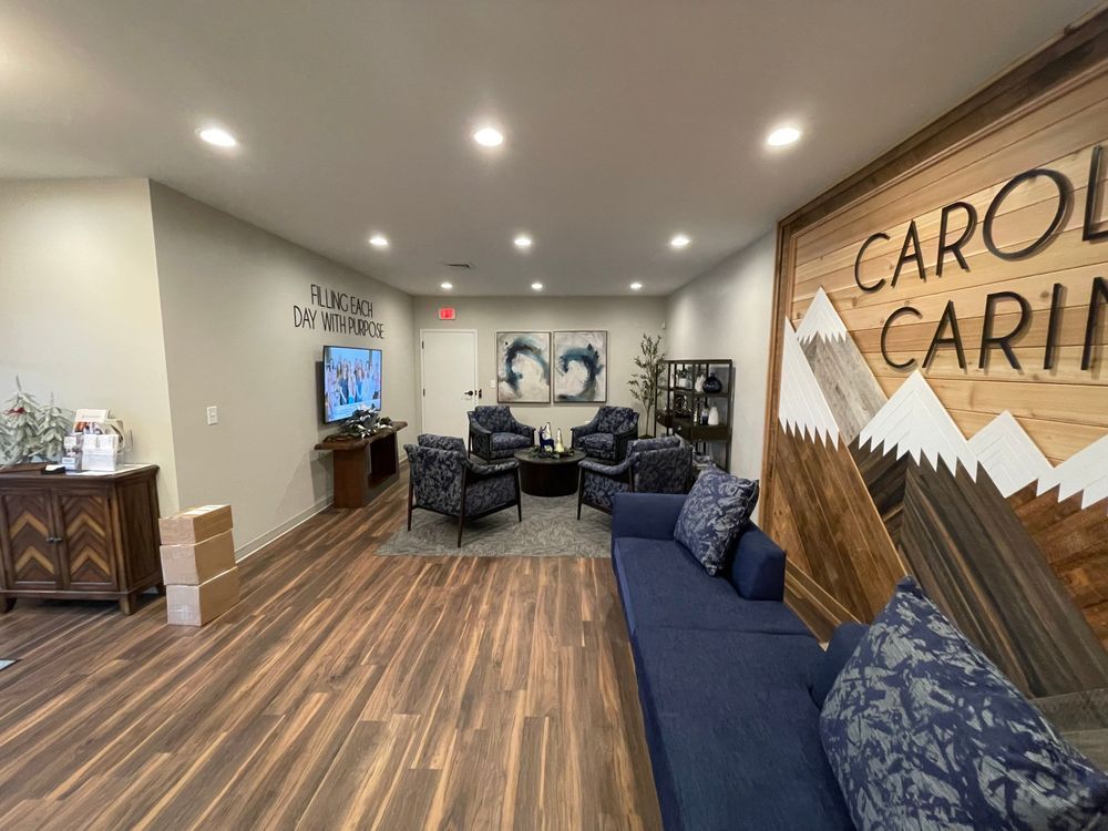 Lobby with blue seating, wood floors, recessed lights, and a large “Carol” wall sign.