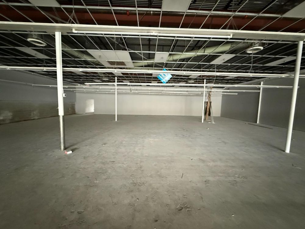 Empty unfinished warehouse interior with concrete floor, exposed ceiling, and support columns