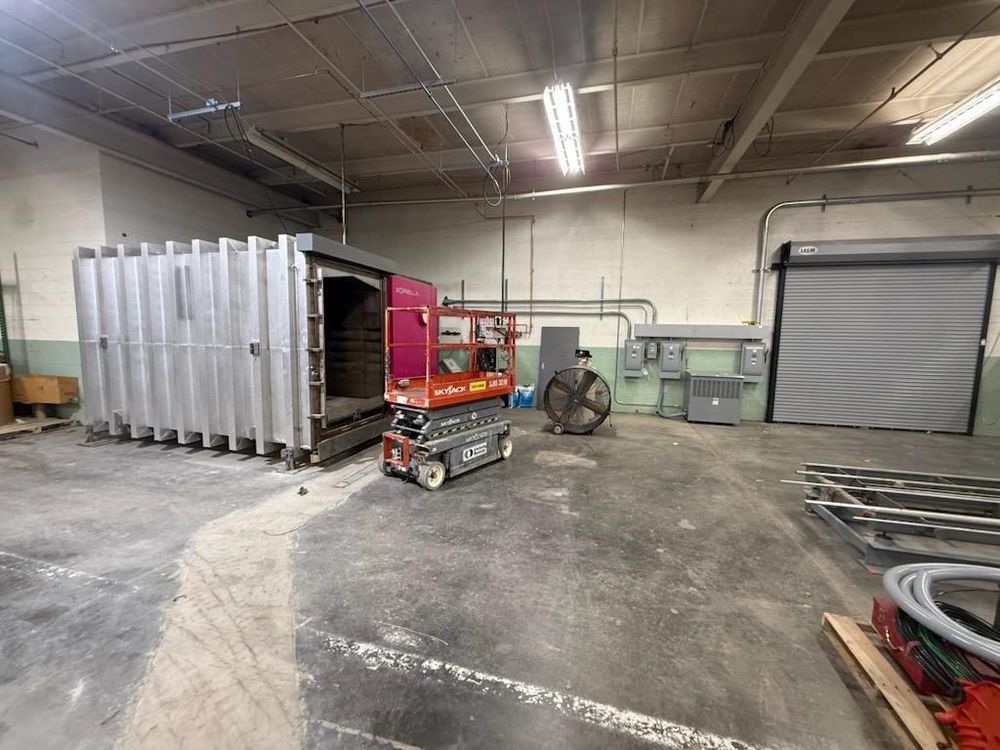 Industrial warehouse with a red lift near metal containers and coiled hoses on the floor