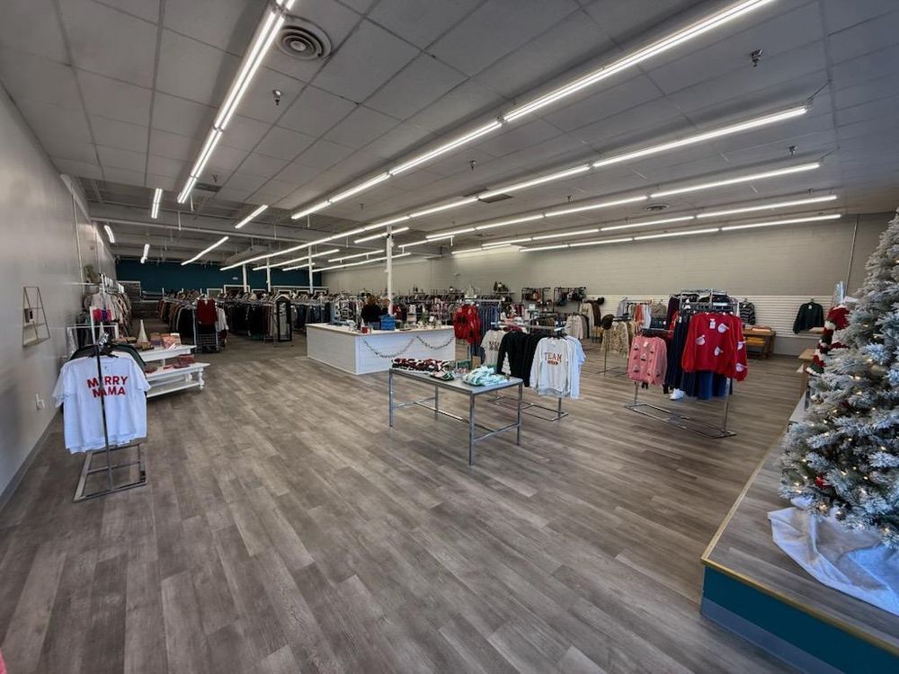 Clothing store interior with racks of apparel, tables, and a decorated Christmas tree