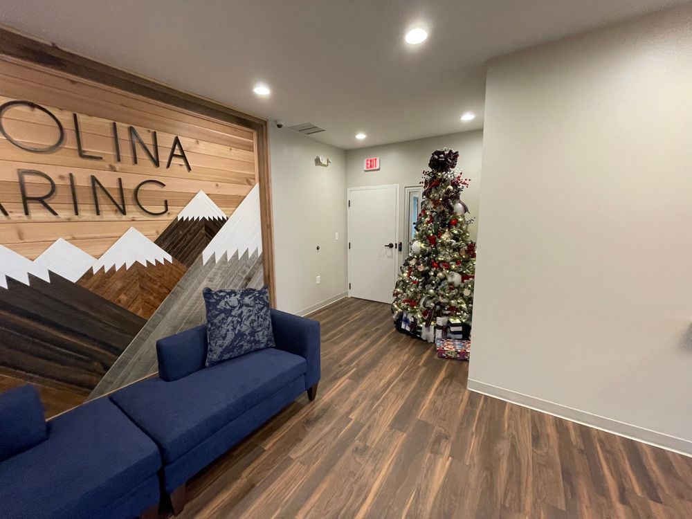 Modern lobby with blue sofas, wood flooring, wall sign, and a decorated Christmas tree near a doorway