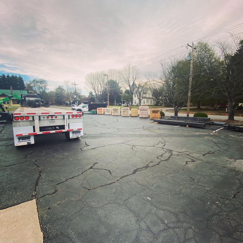Empty cracked parking lot with a flatbed truck and barricades under a cloudy sky