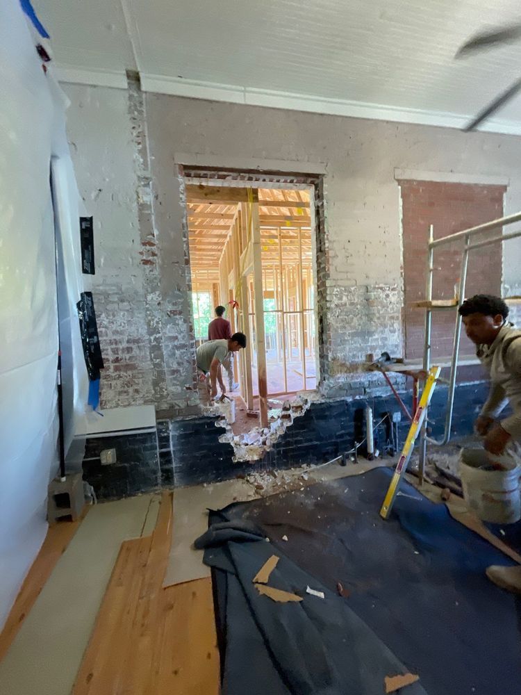 Home renovation scene with workers stripping and repairing walls inside a room