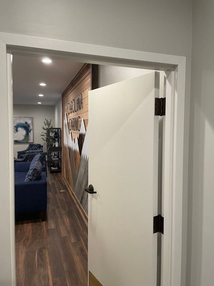 Hallway view into a living room with blue couch, wood floors, and a white door ajar