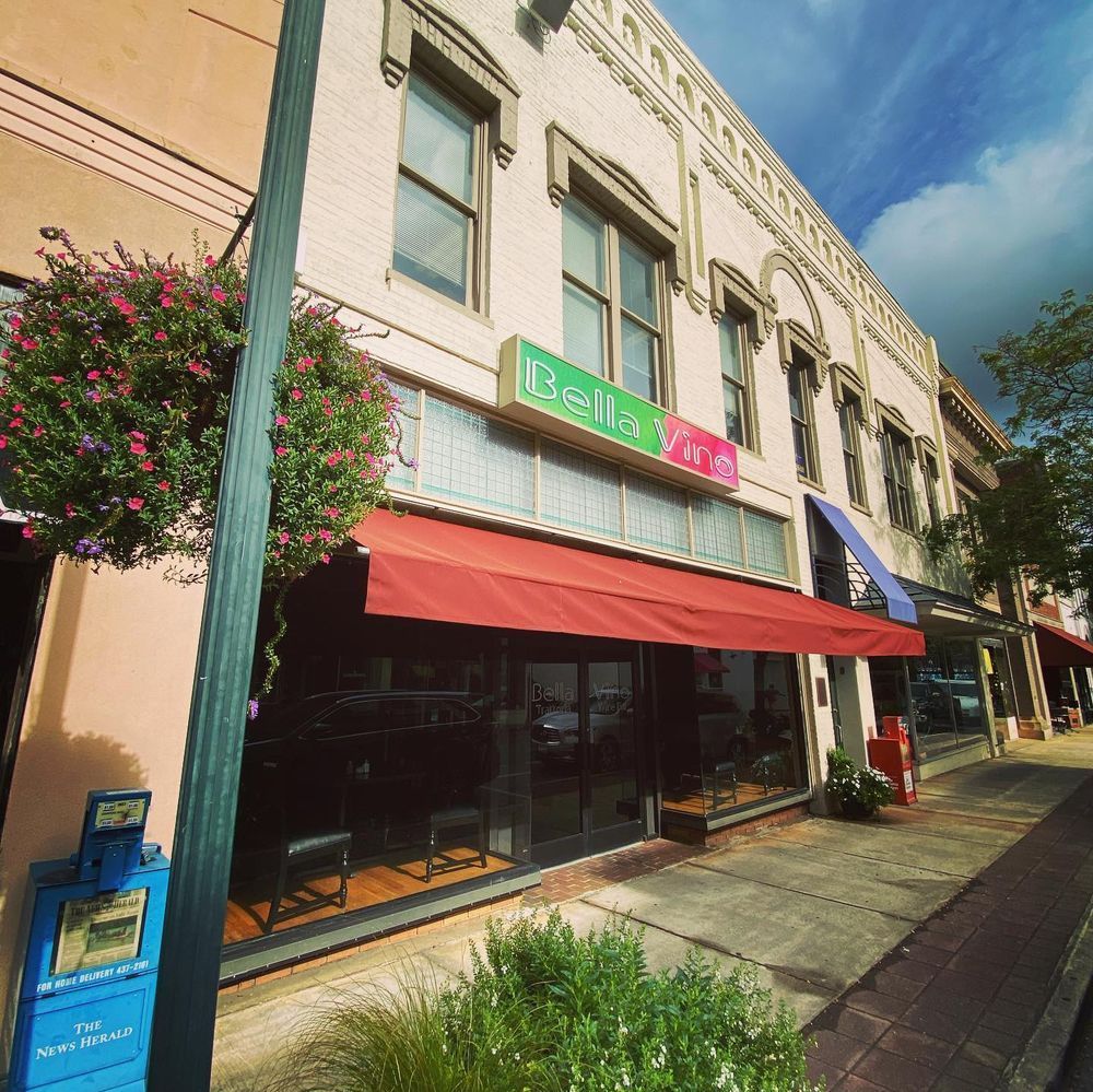 Colorful storefronts with red awning on a sunny street, viewed at an angle