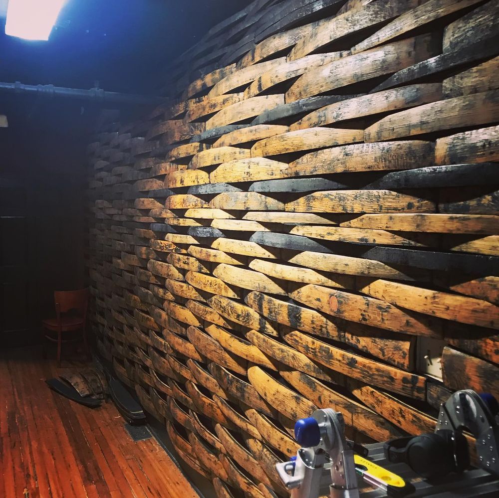 Curved wood-paneled wall with warm lighting in a room, with a bicycle partially visible in the foreground