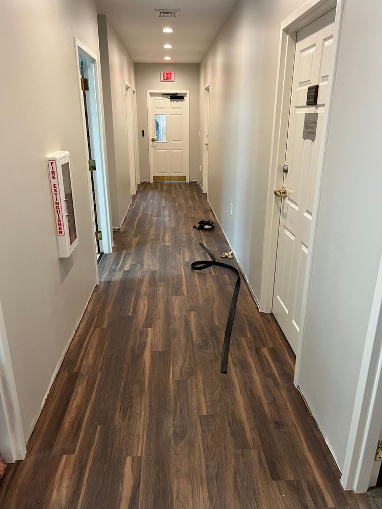 Hallway with wood-look floor, white doors, and a long black cable stretched across the floor.
