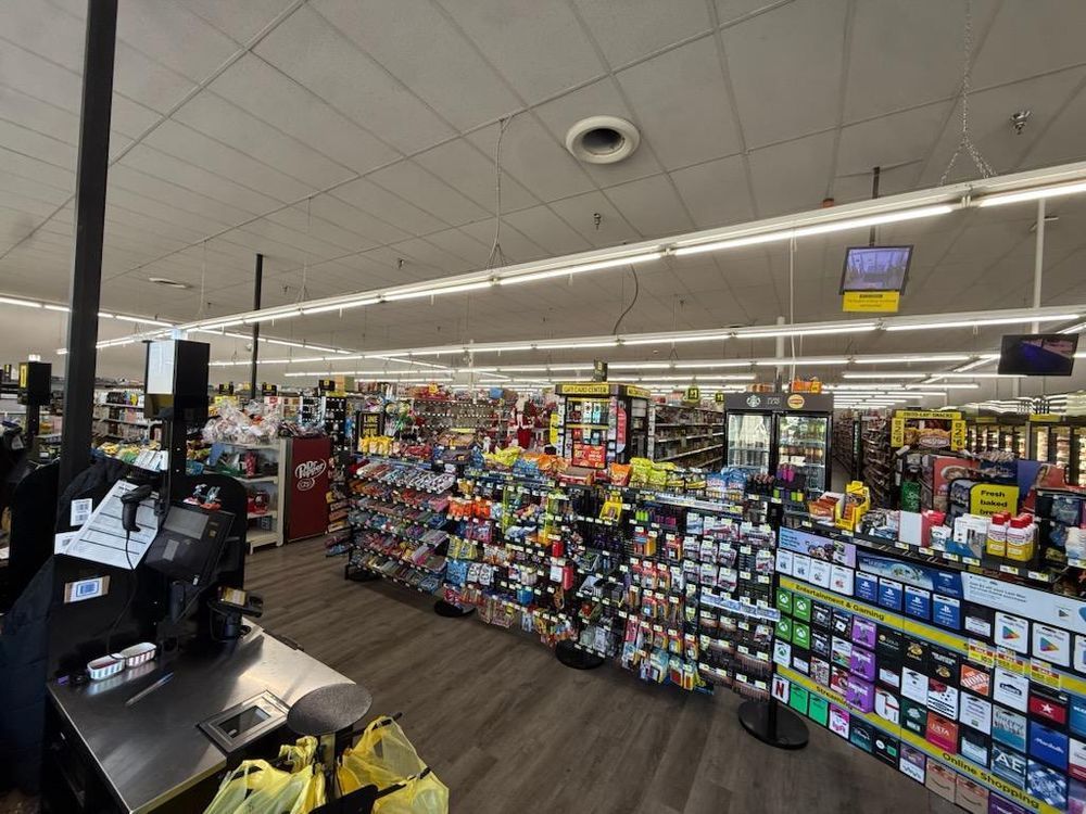 Supermarket checkout area with aisles of colorful products and self-checkout stations