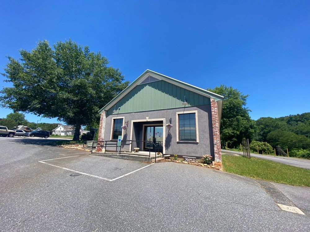 Small storefront with green roof and brick facade beside an empty parking lot on a sunny day