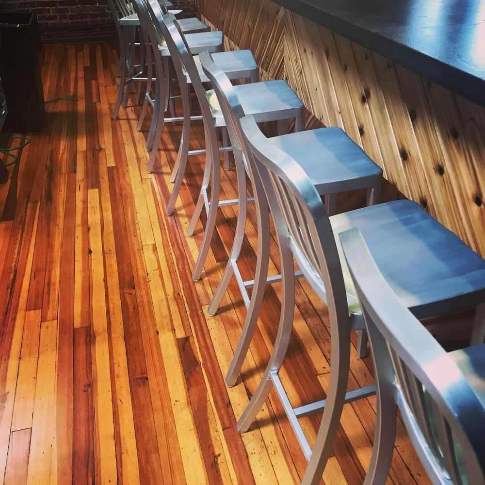Row of metal bar stools beside a wooden counter on a polished wood floor