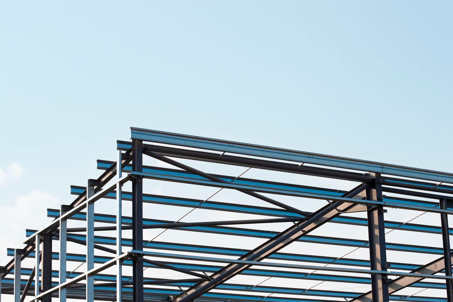 Steel building frame under construction against a clear blue sky