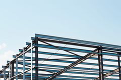 Steel building frame under construction against a clear blue sky