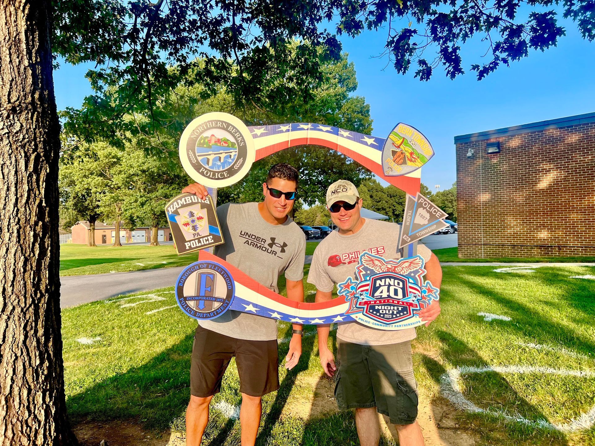 Two men are standing next to each other holding signs in front of a tree.