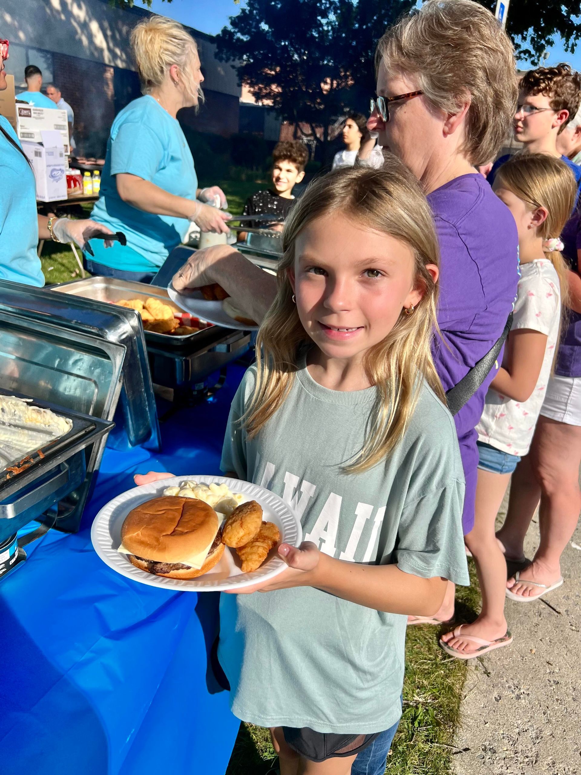 A little girl is holding a plate of food.