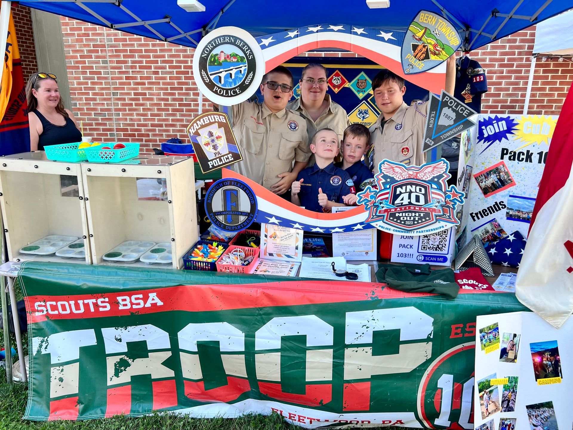 A group of scouts are posing for a picture in front of a troop sign