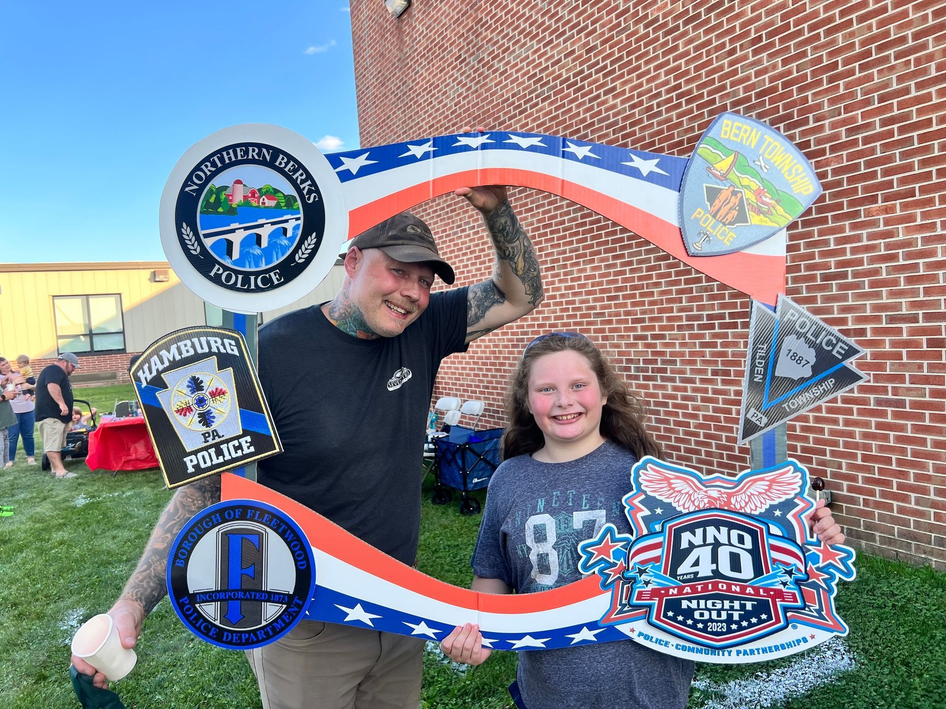 A man and a girl are holding a sign that looks like an american flag.