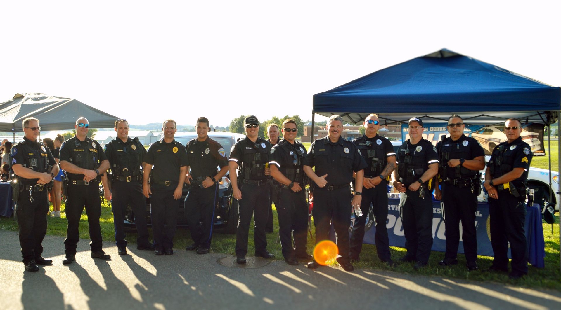 A group of police officers are posing for a picture in front of a blue tent.