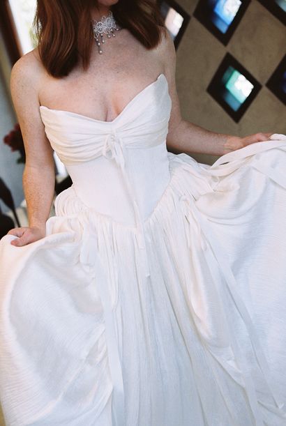 A woman in a bridal gown from Renee Atelier posing in front of a large boulder