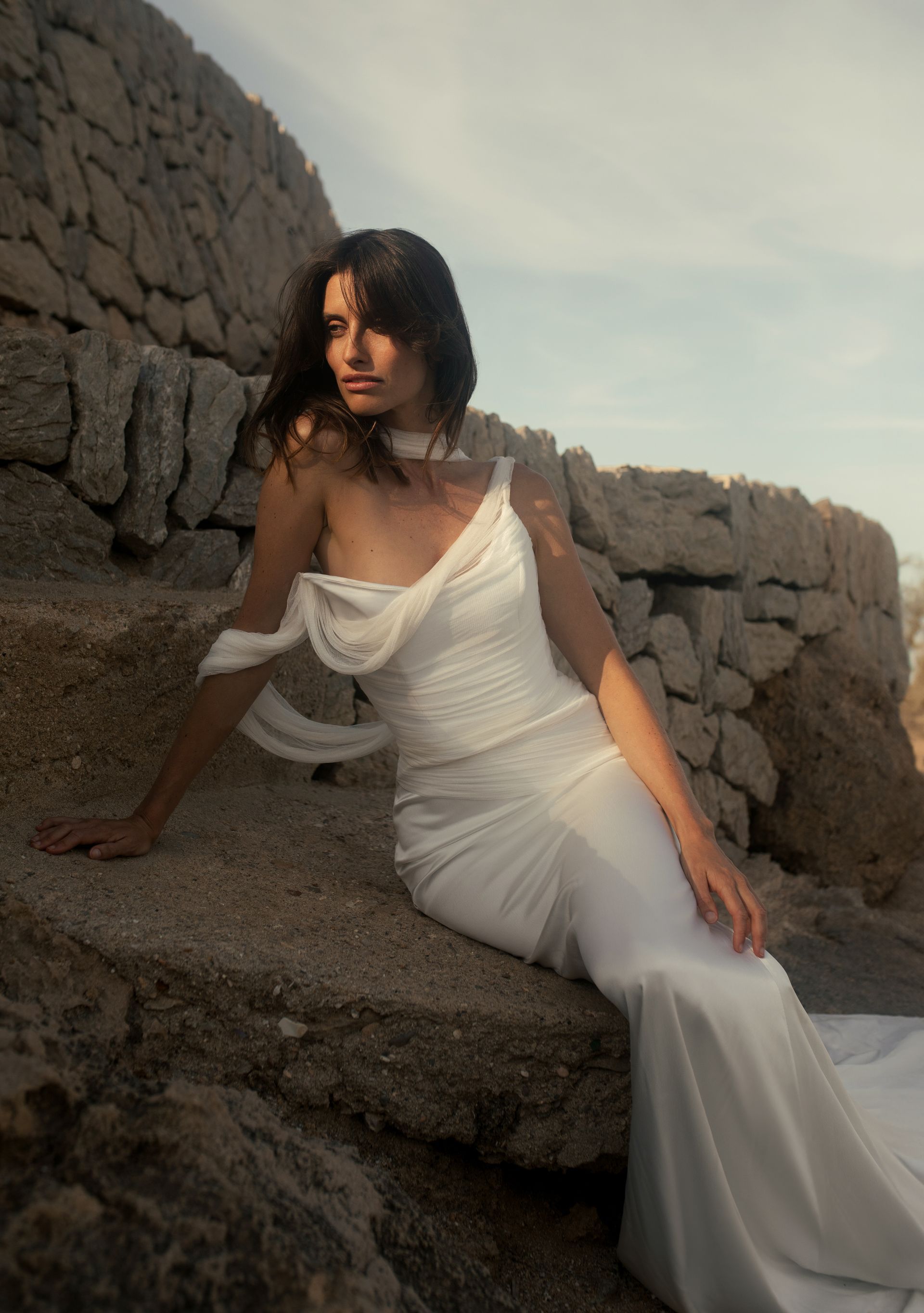 Woman in a wedding dress with a rock wall behind her