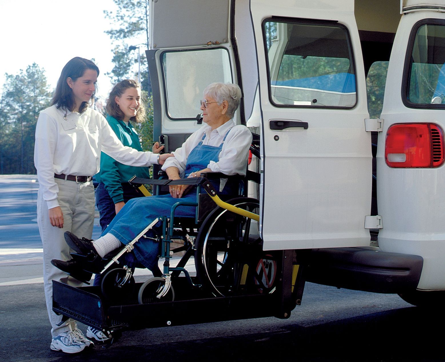 A woman in a wheelchair is being lifted into a van A woman in a wheelchair is being lifted into a van