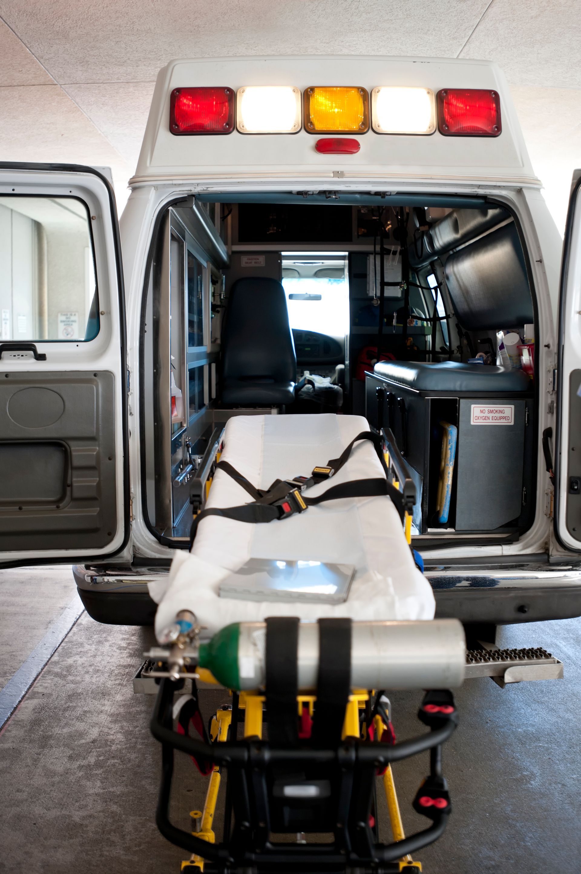 An ambulance driver is carrying a patient on a stretcher out of an ambulance. An ambulance driver is carrying a patient on a stretcher out of an ambulance.